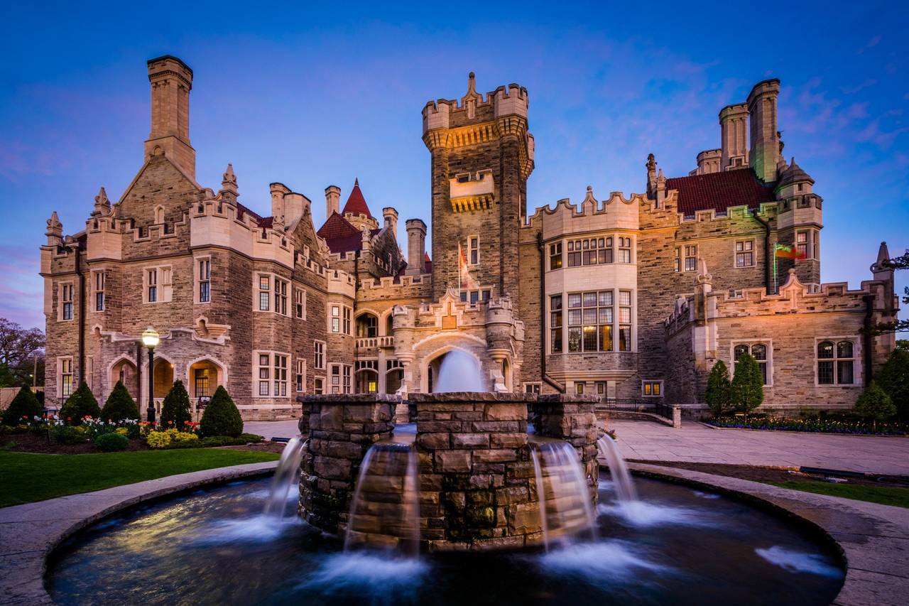 Casa Loma castle with beautiful gardens and Toronto skyline at sunset